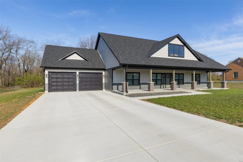 Modern farmhouse style home with a garage, concrete driveway, a front lawn, roof with shingles, and covered porch