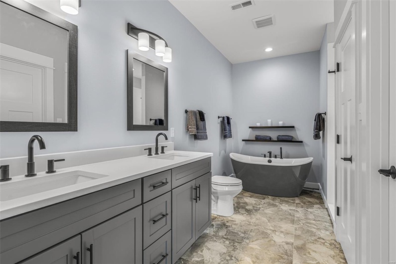 Bathroom featuring double vanity, a sink, a freestanding tub, and visible vents