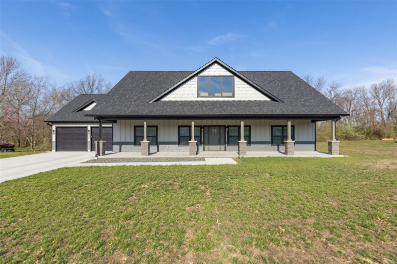 Modern farmhouse style home with an attached garage, a front yard, roof with shingles, driveway, and a porch