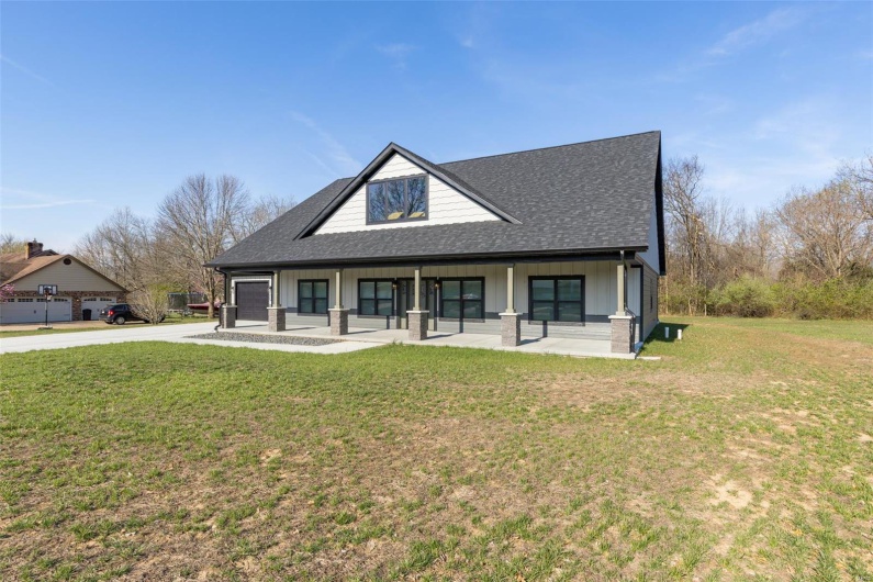 View of front of house featuring a front lawn, covered porch, concrete driveway, and roof with shingles