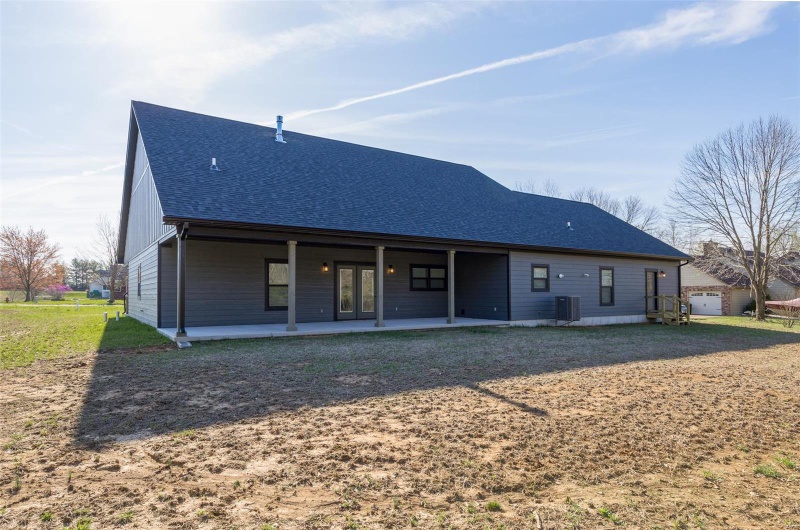Back of house featuring a shingled roof, french doors, and a patio area