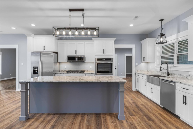 Kitchen with stainless steel appliances, backsplash, a kitchen island, a sink, and visible vents