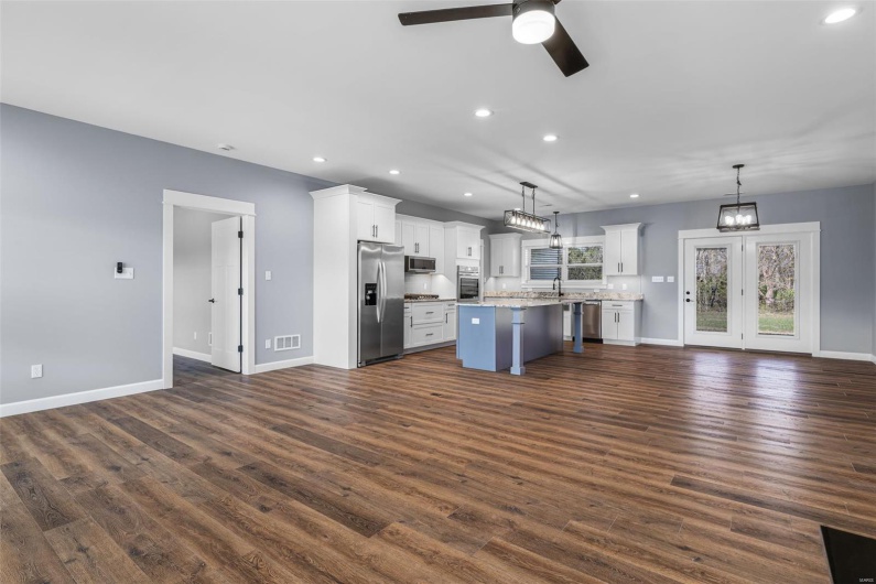 Kitchen featuring white cabinetry, open floor plan, stainless steel appliances, ceiling fan with notable chandelier, and visible vents