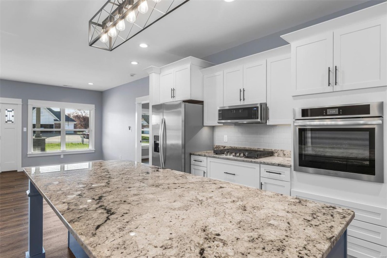 Kitchen with white cabinets, stainless steel appliances, a center island, dark wood-style floors, and backsplash