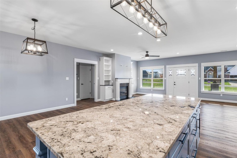 Kitchen featuring open floor plan, a glass covered fireplace, baseboards, and dark wood finished floors