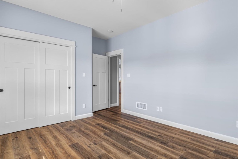 Unfurnished bedroom with dark wood-style flooring, a closet, baseboards, and visible vents