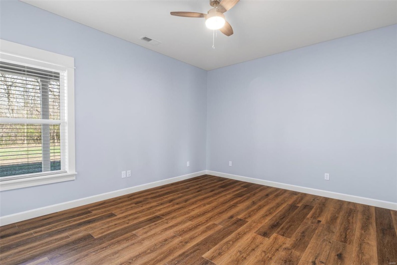 Empty room with a ceiling fan, dark wood-type flooring, baseboards, and visible vents