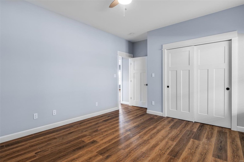 Unfurnished bedroom featuring a ceiling fan, a closet, dark wood-style floors, and baseboards