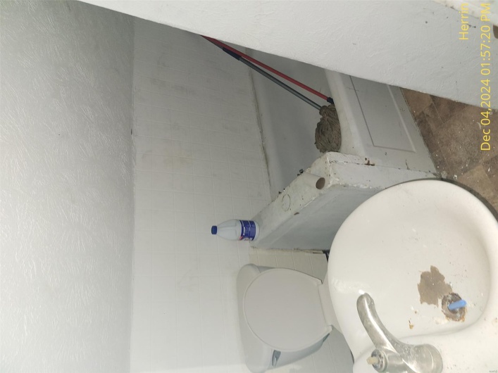 Bathroom featuring a textured ceiling, a washtub, and toilet