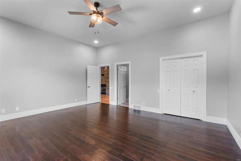 Unfurnished bedroom featuring ceiling fan, a closet, dark hardwood / wood-style flooring, and a high ceiling
