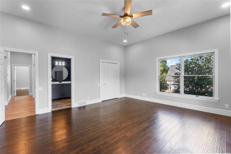 Unfurnished bedroom featuring ceiling fan, a closet, connected bathroom, and dark hardwood / wood-style floors