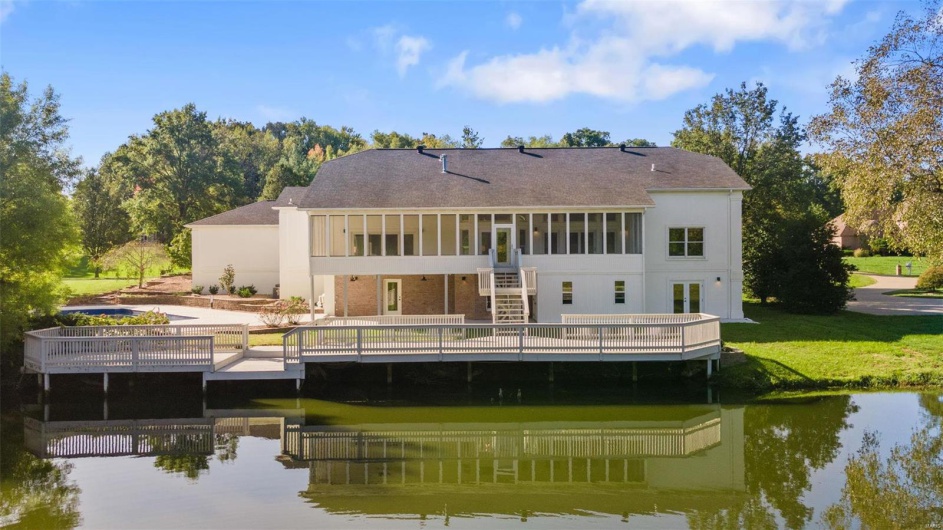 Rear view of house with a yard and a deck with water view