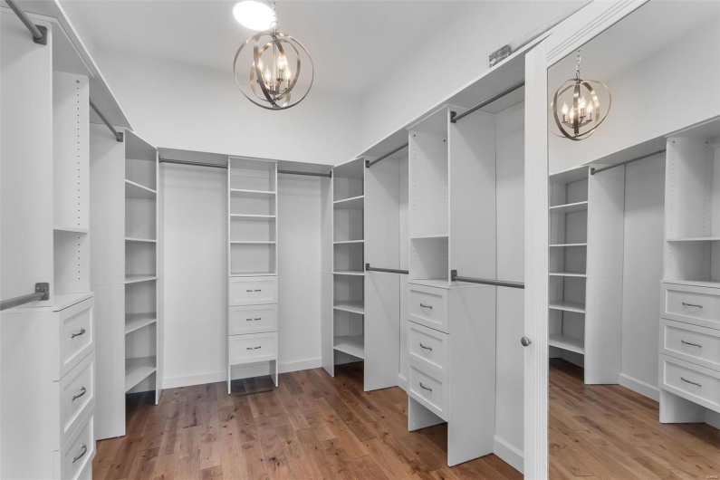 Walk in closet with light hardwood / wood-style floors and a chandelier