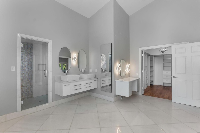 Bathroom with high vaulted ceiling, tile patterned floors, a shower with door, and vanity