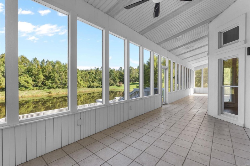 Unfurnished sunroom with ceiling fan, vaulted ceiling, a water view, and a wealth of natural light