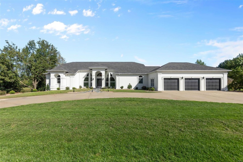 View of front facade featuring a garage and a front lawn