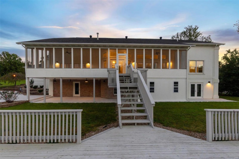 Back house at dusk with a yard, a sunroom, and a patio