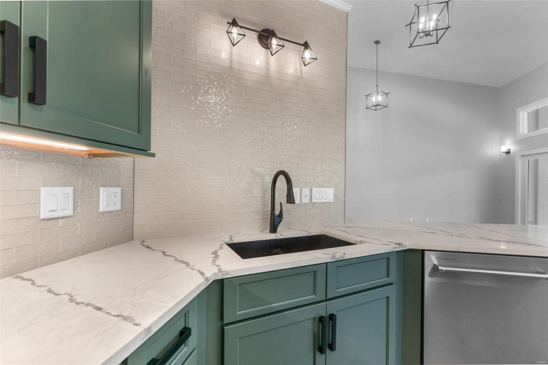Kitchen featuring green cabinetry, light stone countertops, sink, and stainless steel dishwasher