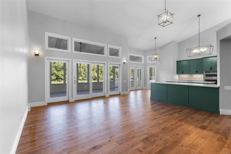 Kitchen featuring high vaulted ceiling, wood-type flooring, green cabinets, and hanging light fixtures