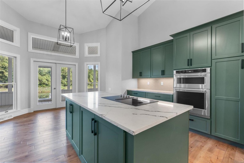 Kitchen featuring pendant lighting, a center island, green cabinets, and light stone counters
