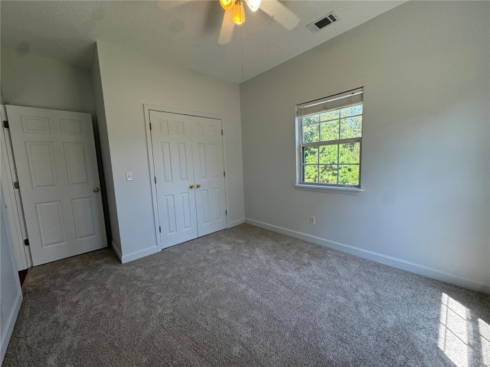 Unfurnished bedroom with a closet, carpet floors, a textured ceiling, baseboards, and visible vents