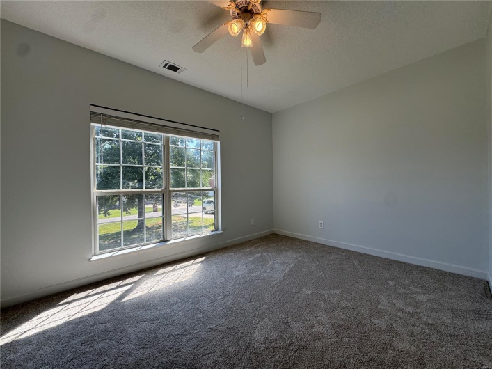 Unfurnished room featuring a textured ceiling, baseboards, visible vents, ceiling fan, and carpet