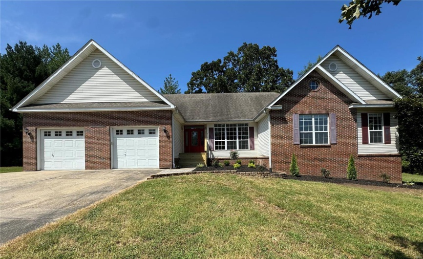 Ranch-style house with brick siding, concrete driveway, a garage, and a front lawn