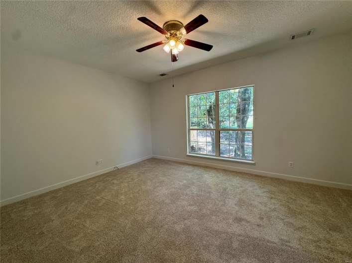 Carpeted spare room featuring visible vents, ceiling fan, and a textured ceiling