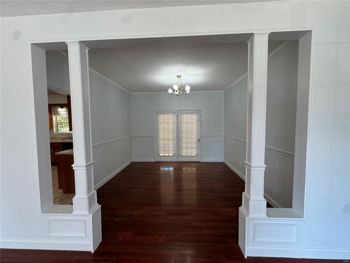 Spare room with ornamental molding, baseboards, a textured ceiling, a notable chandelier, and wood finished floors