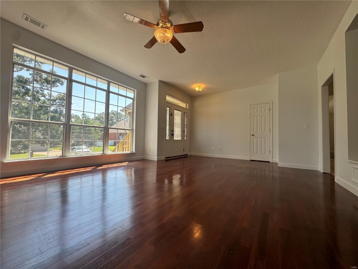 Unfurnished room featuring a textured ceiling, visible vents, wood finished floors, and a ceiling fan