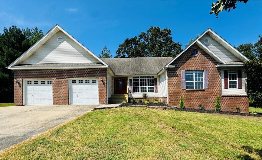 View of front of home with brick siding, concrete driveway, a front lawn, and an attached garage