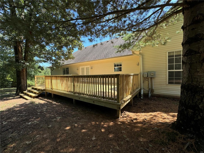 Rear view of house featuring roof with shingles and a wooden deck