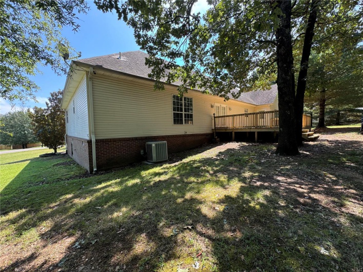 Back of house with central AC unit, a lawn, a shingled roof, and a deck