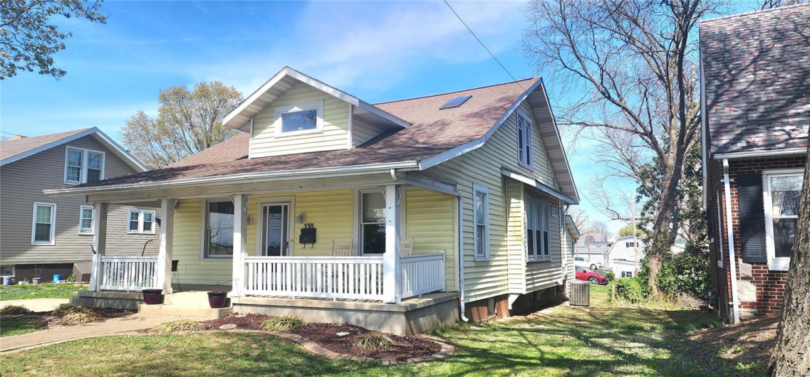 View of front of house featuring central air condition unit, a front lawn, a porch, and roof with shingles