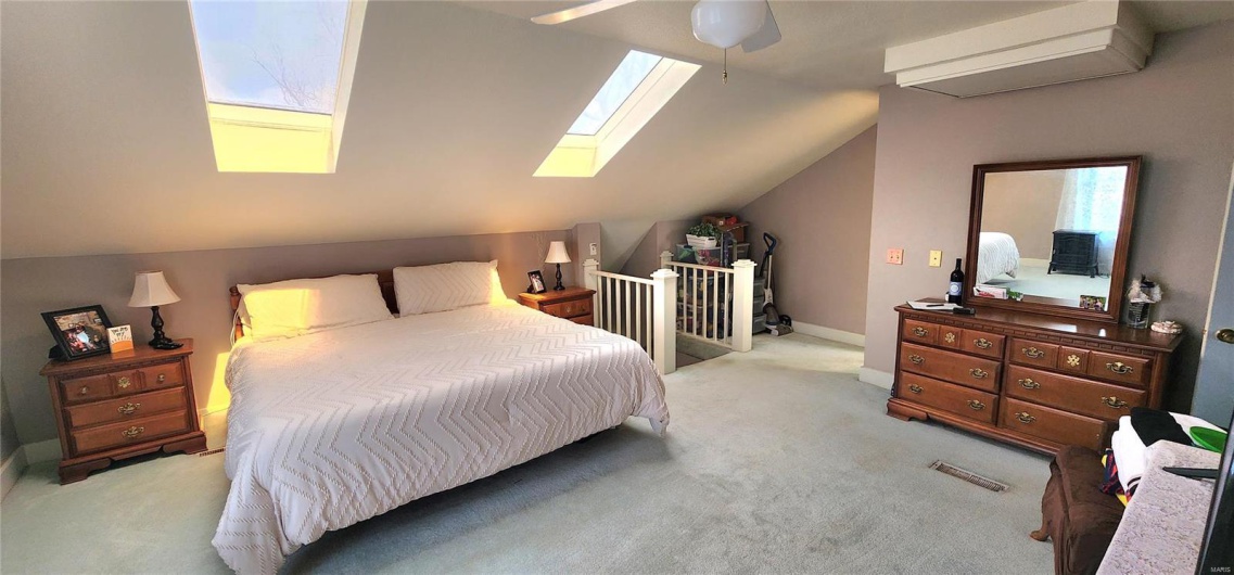 Carpeted bedroom featuring visible vents and vaulted ceiling with skylight
