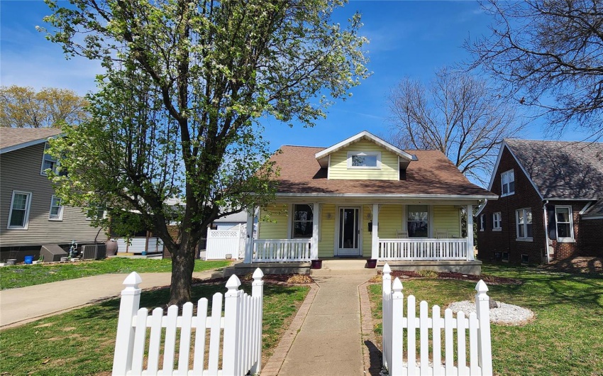 Bungalow-style house featuring central AC unit, a front lawn, a porch, and a fenced front yard