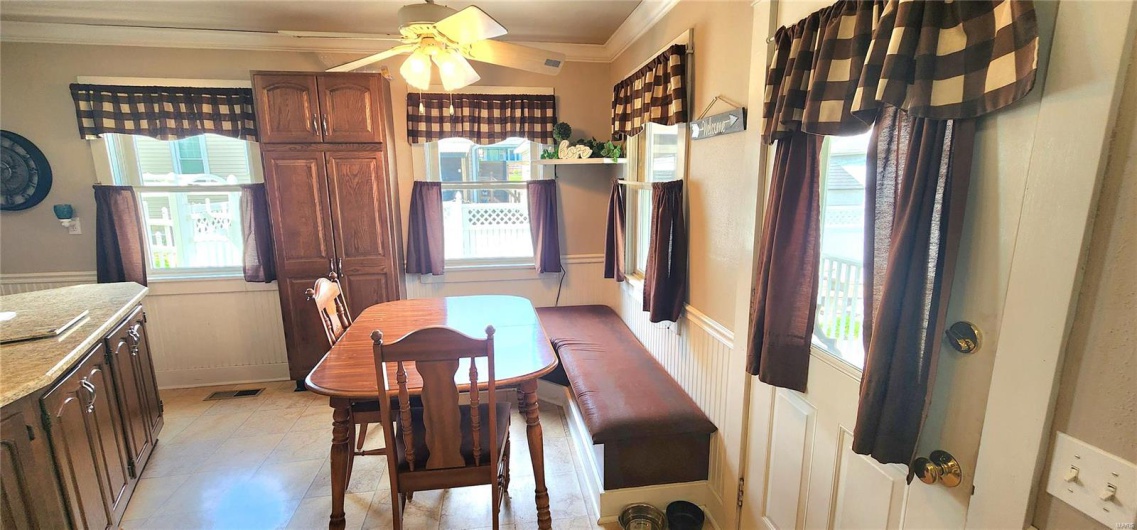 Dining area with a ceiling fan, crown molding, visible vents, a decorative wall, and wainscoting
