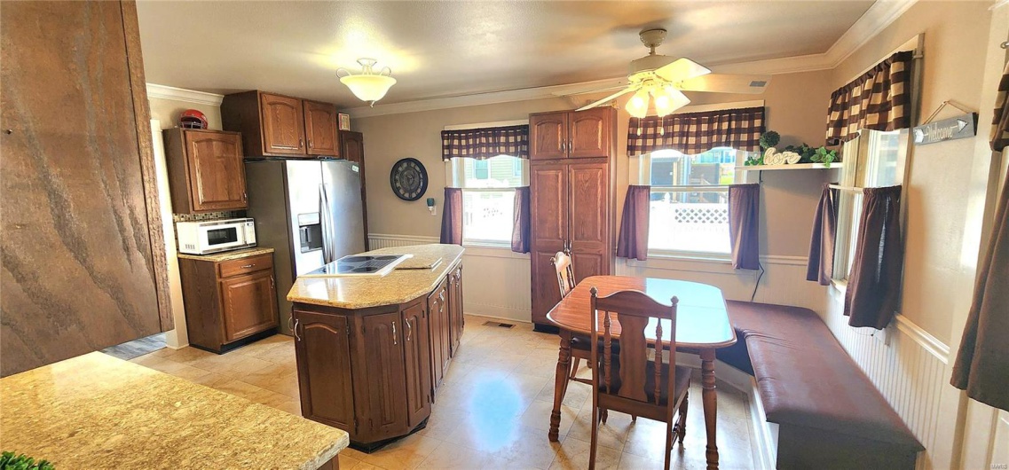 Kitchen featuring a ceiling fan, crown molding, white microwave, and a kitchen island