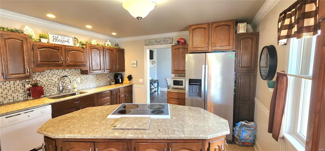 Kitchen with light countertops, a sink, a kitchen island, and white appliances