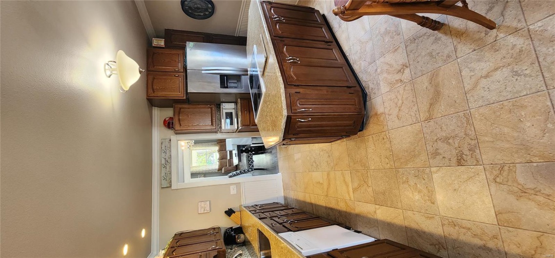 Kitchen with a wainscoted wall, ornamental molding, a sink, dishwashing machine, and fridge