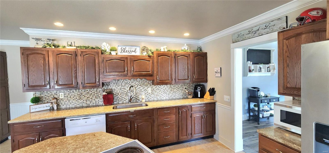 Kitchen with decorative backsplash, ornamental molding, a sink, and white appliances