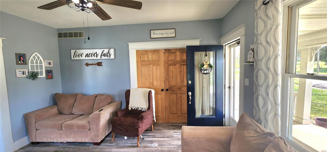 Living area featuring a wealth of natural light, visible vents, a ceiling fan, and wood finished floors