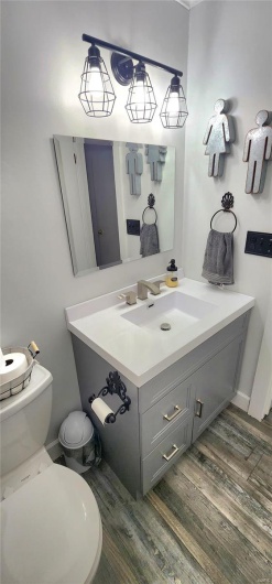 Bathroom featuring toilet, vanity, and wood finished floors