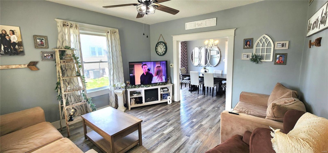 Living area featuring wood finished floors and ceiling fan with notable chandelier
