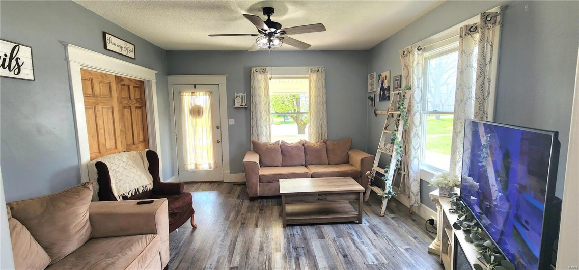 Living area featuring baseboards, wood finished floors, a healthy amount of sunlight, and a ceiling fan