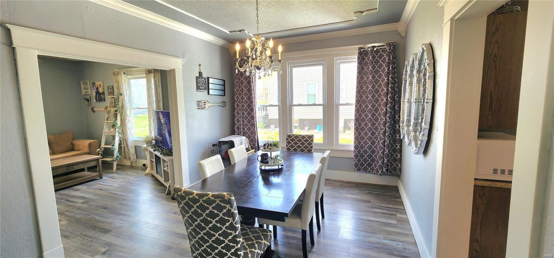 Dining room featuring baseboards, wood finished floors, a chandelier, and crown molding