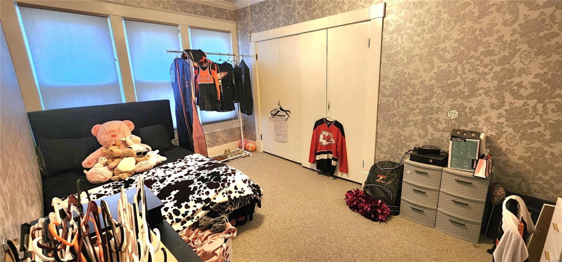 Carpeted bedroom with a closet, wallpapered walls, and crown molding