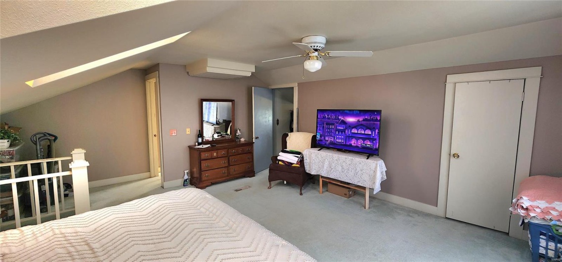 Bedroom with a ceiling fan, carpet floors, and vaulted ceiling with skylight