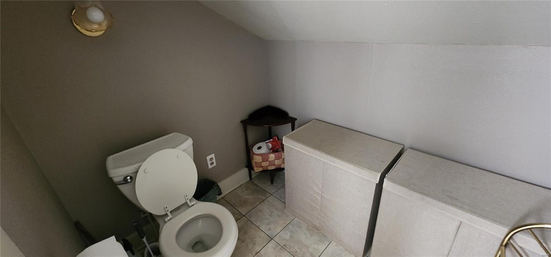 Bathroom featuring toilet, vaulted ceiling, and tile patterned floors