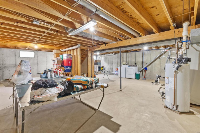 Basement featuring water heater and washer and clothes dryer